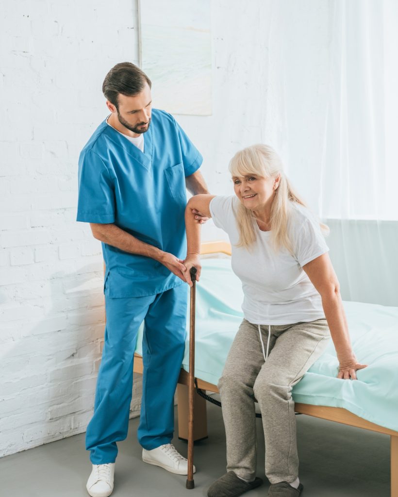 male-nurse-helping-senior-woman-with-walking-stick